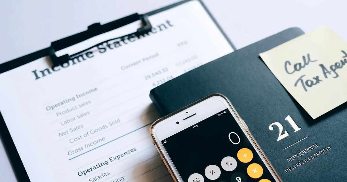 Smartphone displaying calculator app on top of financial income statement documents — Shopify merchant accounting blind spots for QuickBooks Online